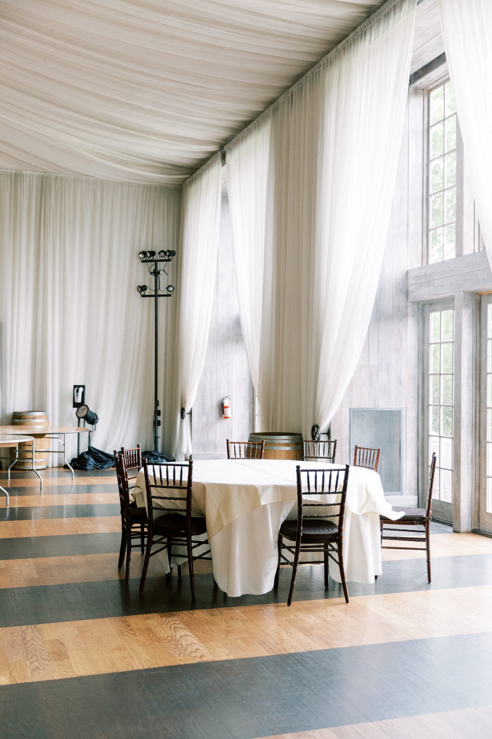 The reception space at Veritas has round tables, chairs and a white curtain