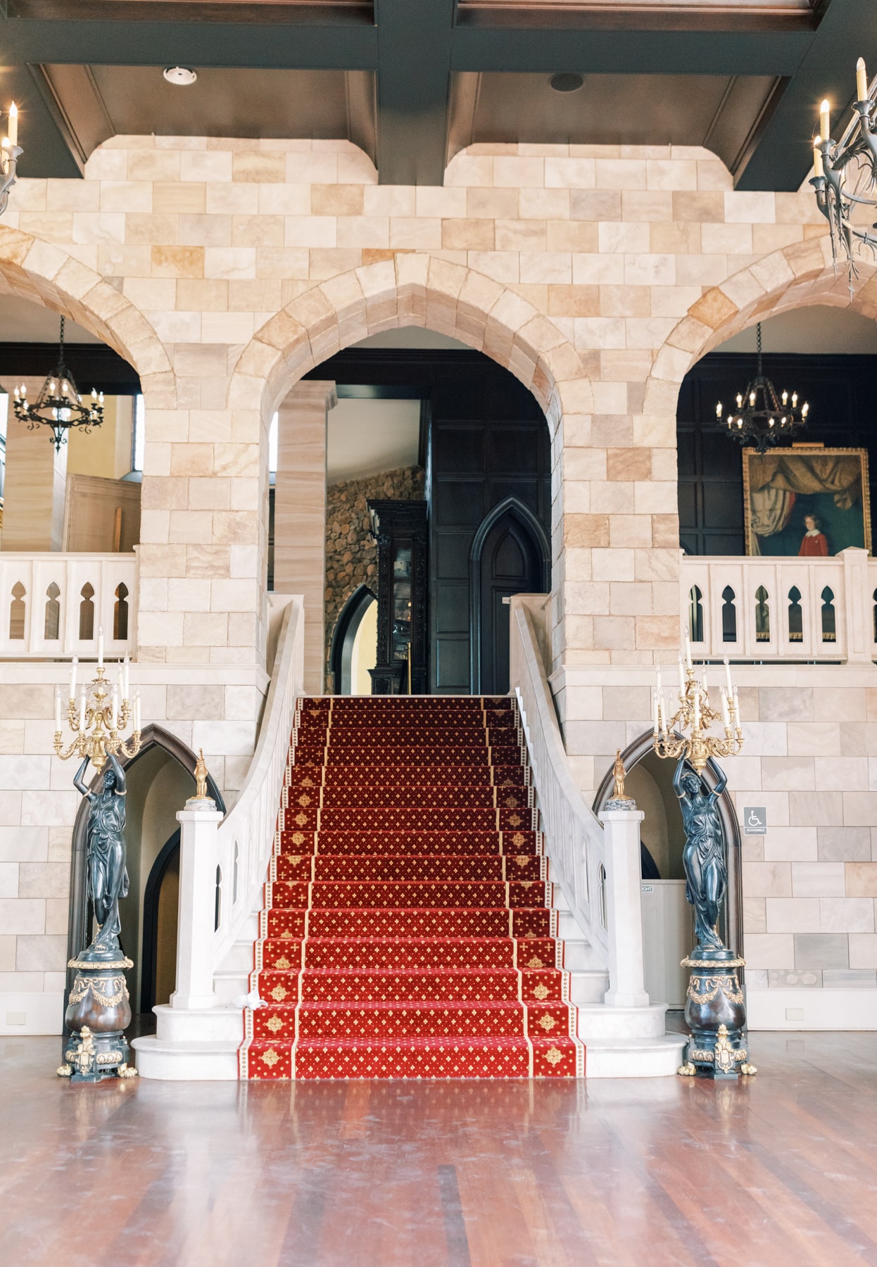 The grand staircase  is lined with bright red carpet, and sand colored stone.
